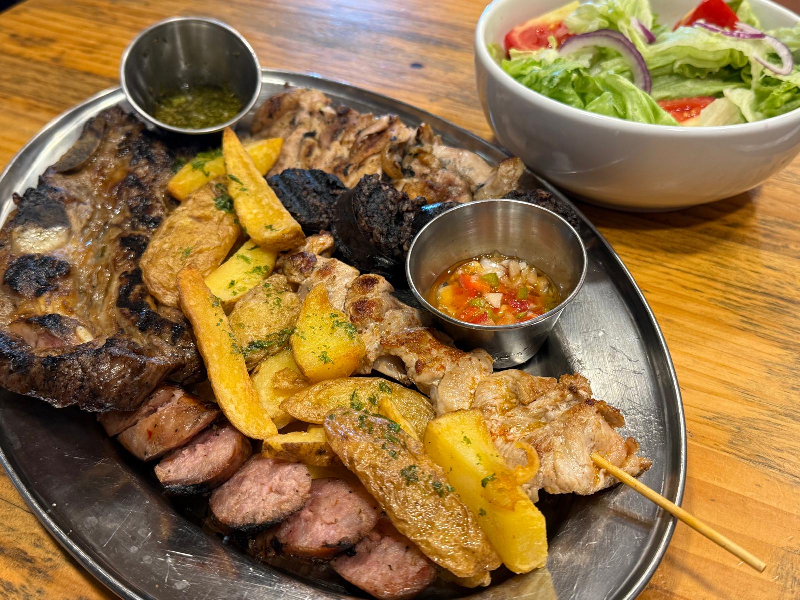 Parrillada de carnes con ensalada fresca de lechuga, tomate y cebolla